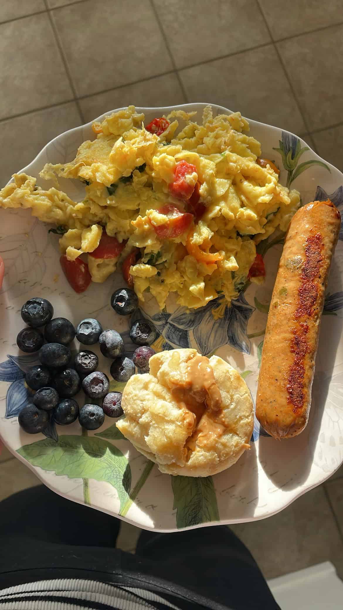 biscuits, chicken sausage, blueberries and scrambled eggs with tomatoes on a white flower