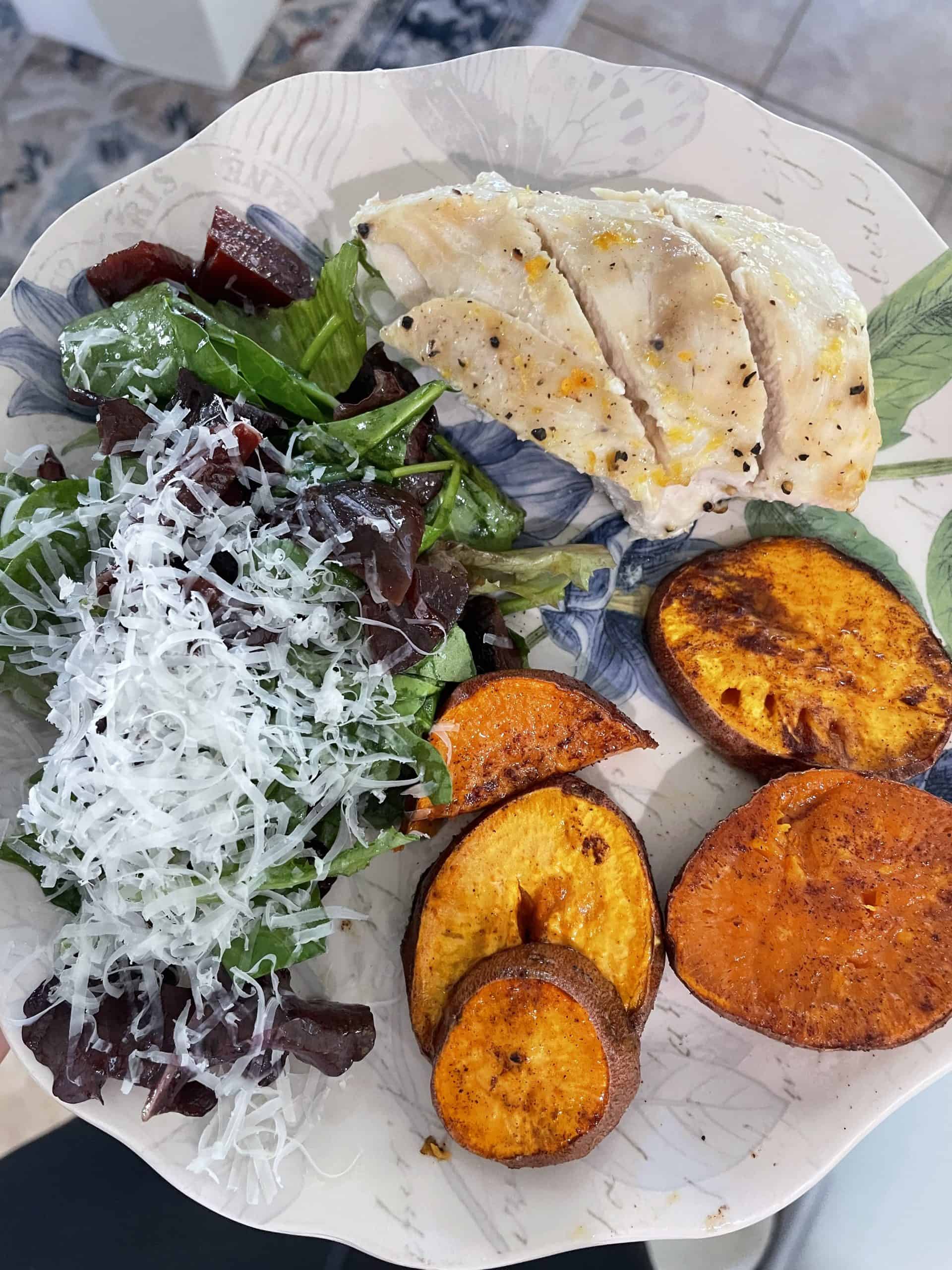 chicken breast, slices sweet potatoes and a salad on a decorative white plate