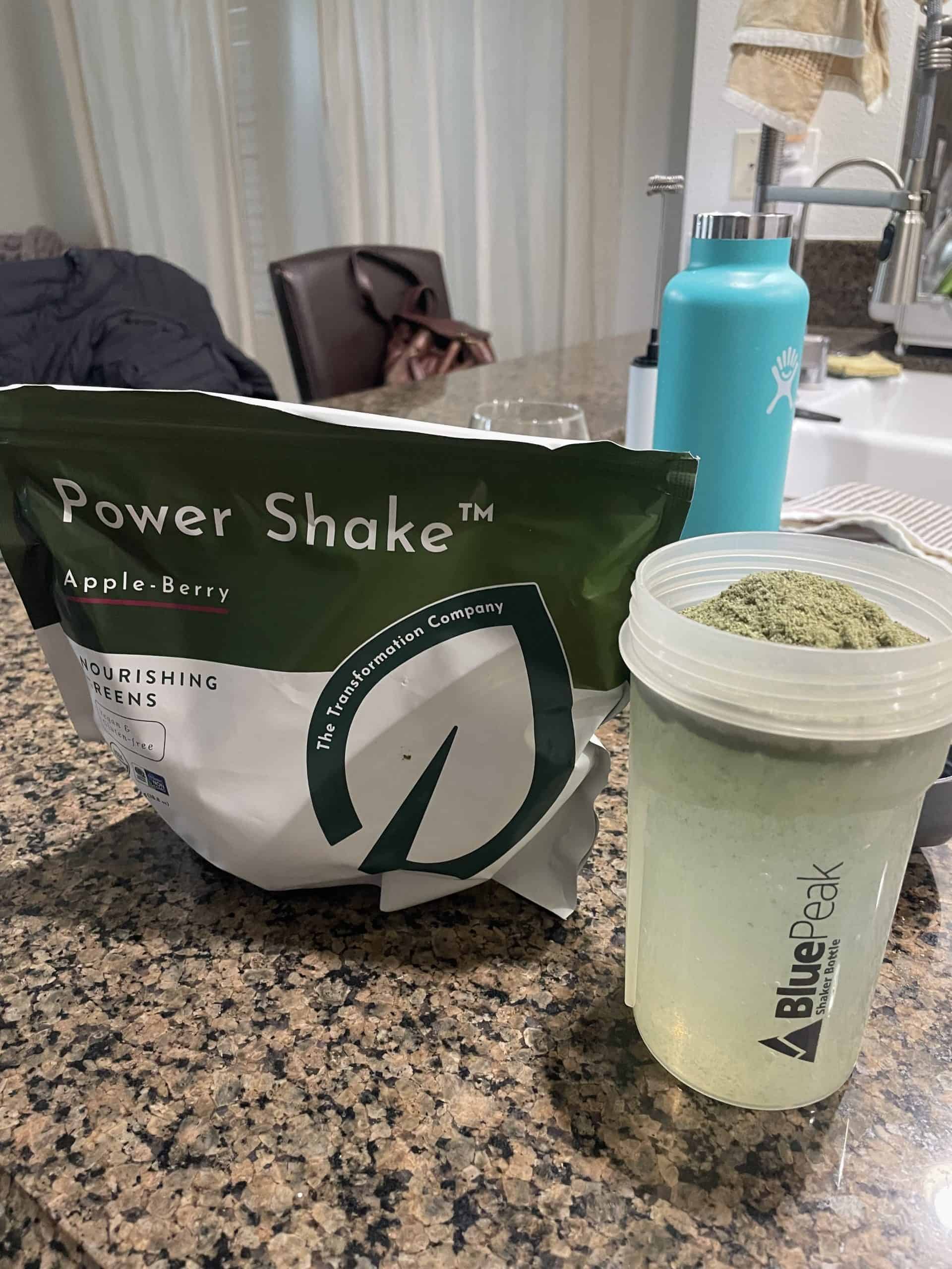 a green drink in a shaker cup with the product bag on the counter titled 'power shake'