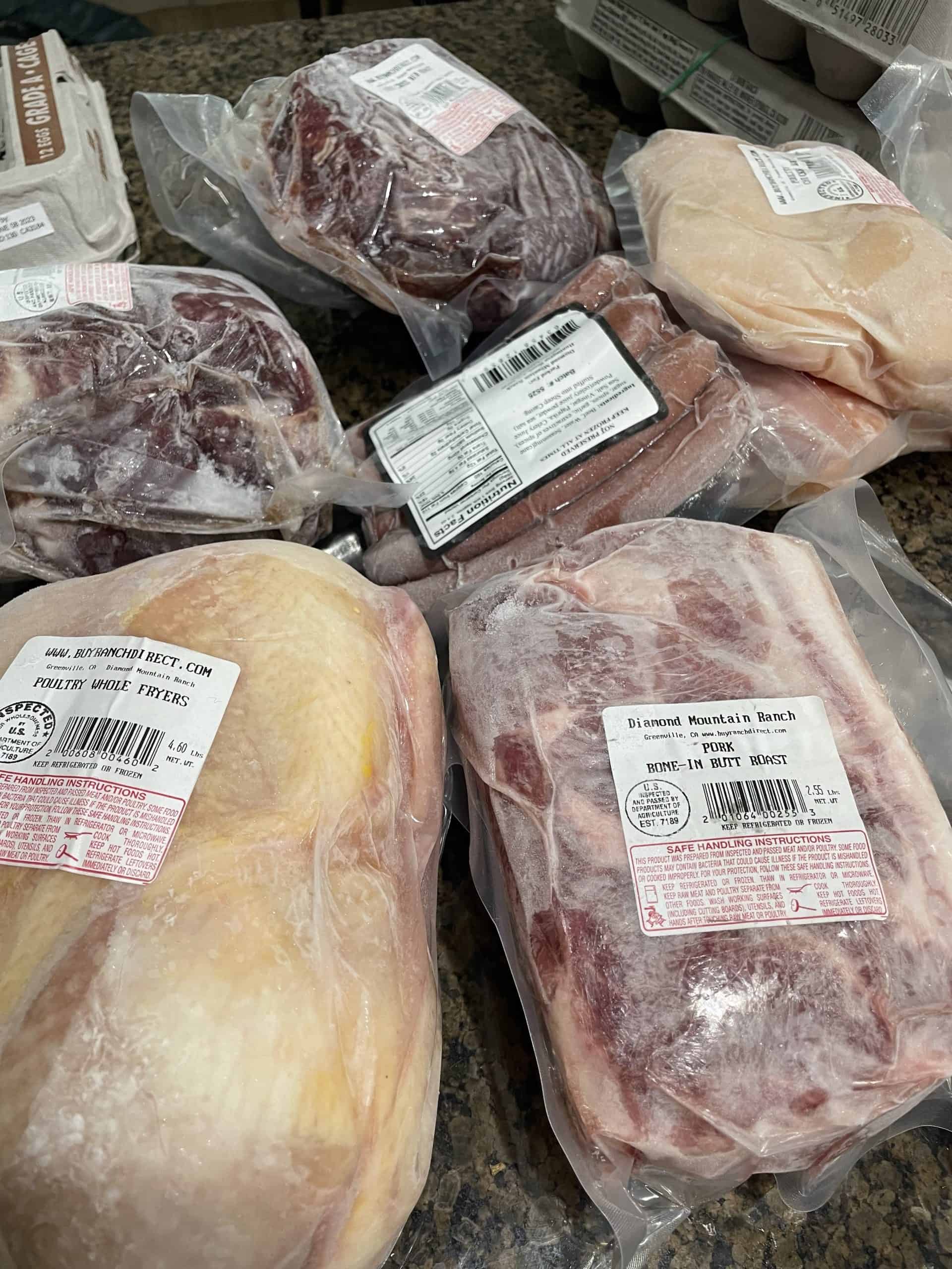 packaged meat on a countertop consistently of a while chicken, pork roast and hot dogs
